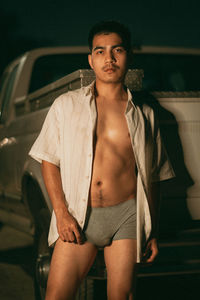 Portrait of young woman standing by car