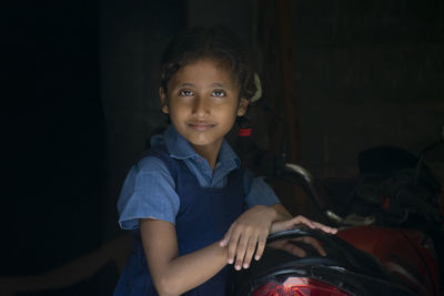 Portrait of girl wearing school uniform standing by motorcycle