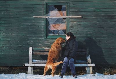 Rear view of woman with dog on snow