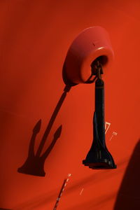 Low angle view of illuminated lamp against orange wall