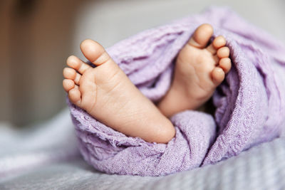 Low section of baby girl lying on bed at home