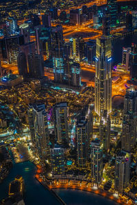 High angle view of illuminated street amidst buildings in city at night