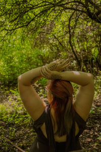 Rear view of woman with arms raised