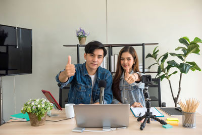 Portrait of young woman using laptop while sitting on table