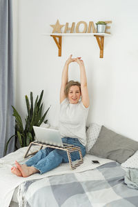 Portrait of young woman sitting on bed at home