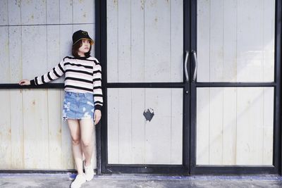 Portrait of young woman standing against wall