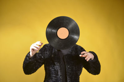 Woman with turntable standing against colored background