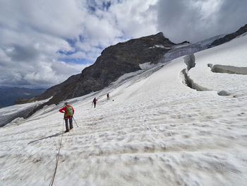 People on snowcapped mountain against sky