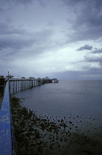 Pier on sea against cloudy sky