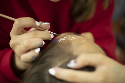 Face pattern. applying paint to skin. thin brush. girl draws on skin.