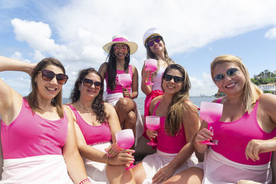 Female friends on top of a boat against the sea in the background.