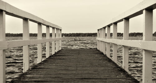 Footbridge over sea against clear sky