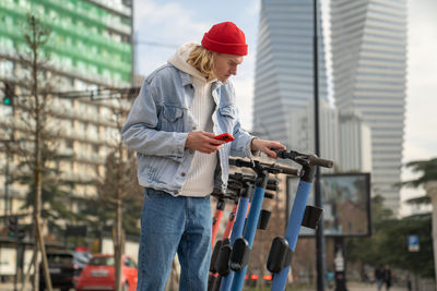 Portrait of young woman using mobile phone while standing in city