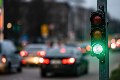 A city crossing with a semaphore on blurred background with cars in the evening streets, green light