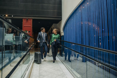 Full length of businessman and businesswoman discussing while walking in hotel lounge