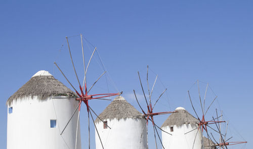 Low angle view of traditional windmills against blue sky