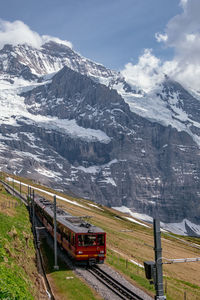 Train on railroad track by mountain against sky