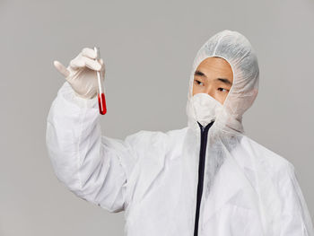 Female doctor holding dentures while standing against wall