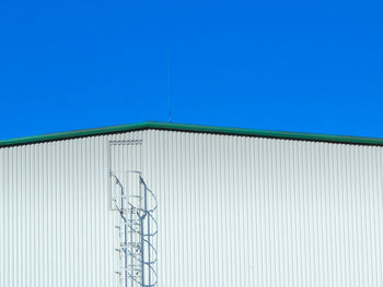 Rooftop of corrugated iron plated industrial hall with ladder to rooftop door.
