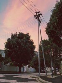 Low angle view of electricity pylon against sky during sunset