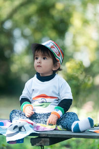 Portrait of cute baby boy sitting on field