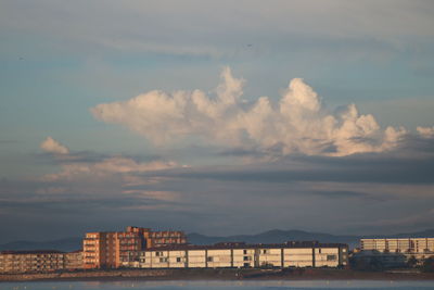 Buildings by sea against sky during sunset