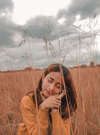 Portrait of beautiful young woman on field against sky