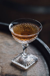 Whiskey cocktail in vintage hobnail glass atop wooden barrel