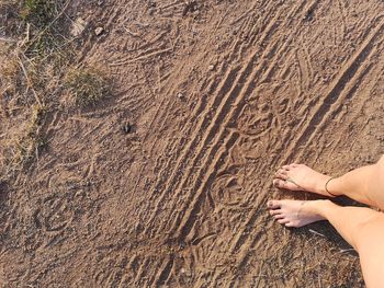 Low section of woman standing on sand