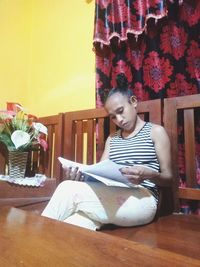 Young woman sitting on table at home