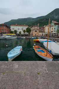 Boats moored by lake against buildings in city