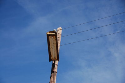 Low angle view of telephone pole against blue sky