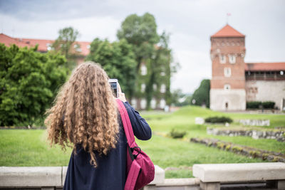 Rear view of woman photographing outdoors