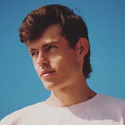 Portrait of young man looking away against blue sky