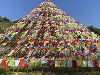 Low angle view of flags hanging on field against clear sky