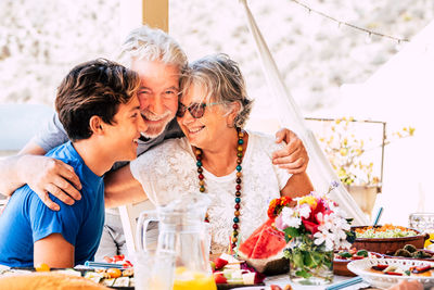 Smiling grandparents with grandson sitting at restaurant