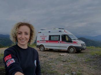 Portrait of smiling teenage girl standing on mountain against sky