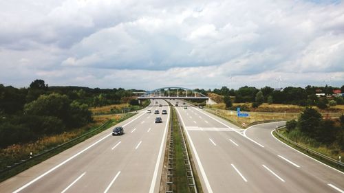 Cars on road against cloudy sky during sunny day