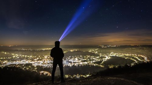 Man with arms outstretched against sky at night