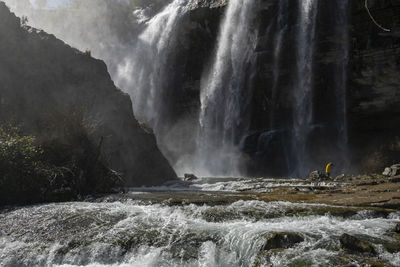 Man standing against waterfall