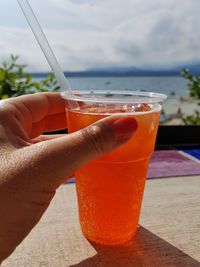 Cropped hand of woman holding drink on table