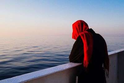 Woman standing by sea against clear sky