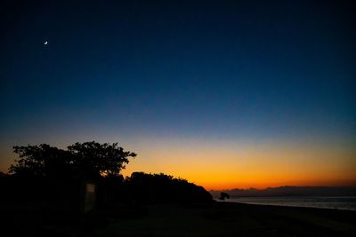 Scenic view of silhouette trees against clear sky at sunset