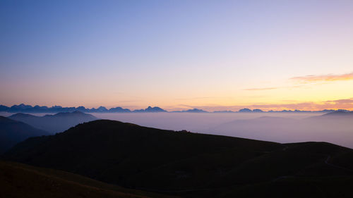 Scenic view of silhouette mountains against romantic sky at sunset