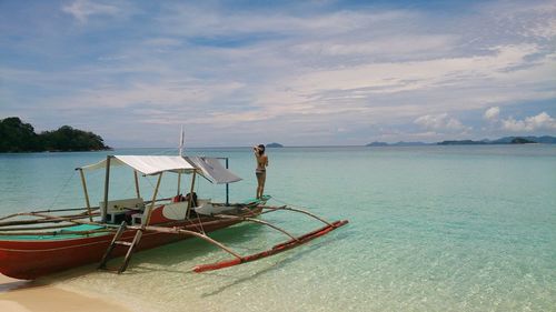 Rear view of woman standing on outrigger canoe at palawan