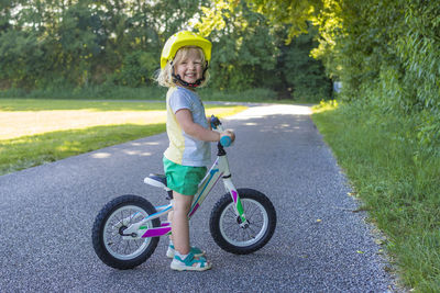 Full length portrait of cute boy with bicycle standing on road
