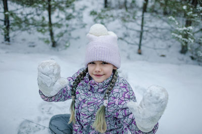 Portrait of smiling girl standing on snow covered field