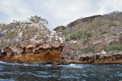 Scenic view of rocks by sea against sky