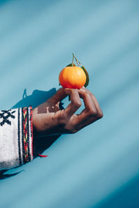 Midsection of woman holding fruit against blue sky