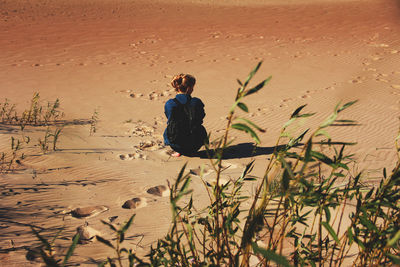 Rear view of woman sitting on sand at beach